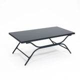 A black rectangular folding table with a metal frame and flat top is elegantly paired with an outdoor seating set, creating a sleek contrast against the plain white background.