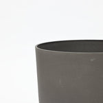 Close-up of the upper edge of a gray, cylindrical concrete planter from a durable planter set against a plain white background.