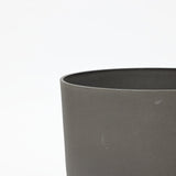 Close-up of the upper edge of a gray, cylindrical concrete planter from a durable planter set against a plain white background.
