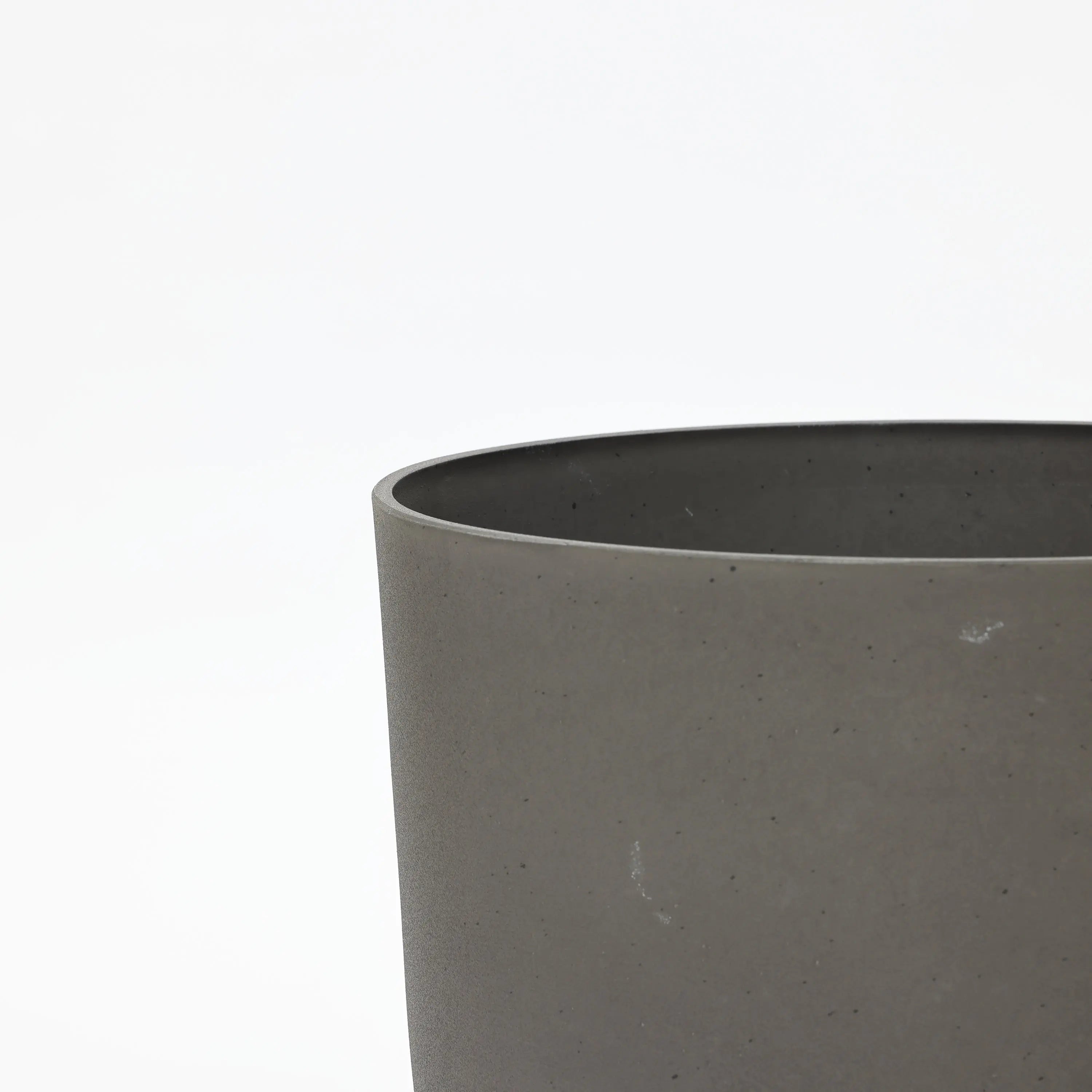 Close-up of the upper edge of a gray, cylindrical concrete planter from a durable planter set against a plain white background.