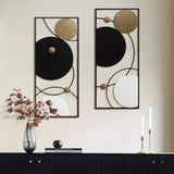 Modern abstract wall decor in a stunning two-piece set showcases circular designs in black, white, and gold. Placed on a sleek black sideboard, the art is complemented by dried flowers in a vase and the soft glow of two lit candles.
