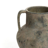 Close-up of the LuxenHome Rustic mottled grey terracotta urn vase, 12.1 h, featuring one curved handle. Its weathered surface displays shades of gray and brown, embodying a classic rustic design against a plain white background.