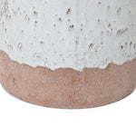 Close-up of a two-tone ceramic vase with a textured surface, featuring a white upper half and an unglazed brown base. Its bottle-like design adds an elegant touch.