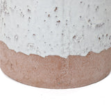 Close-up of a two-tone ceramic vase with a textured surface, featuring a white upper half and an unglazed brown base. Its bottle-like design adds an elegant touch.