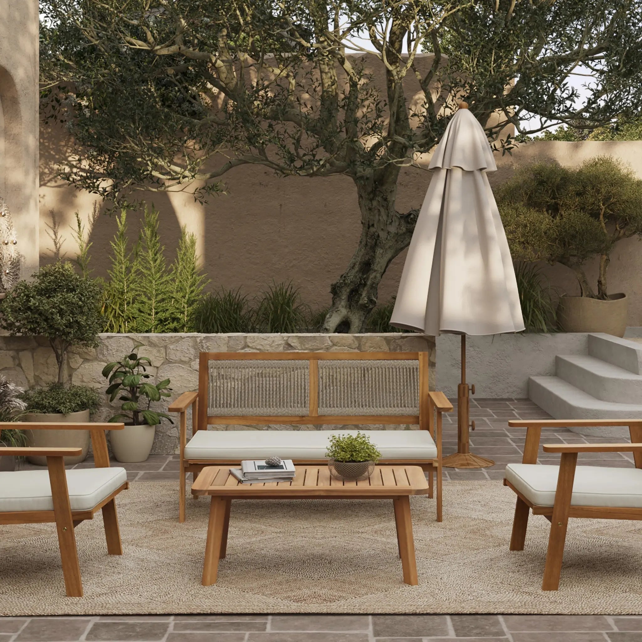 Outdoor patio featuring an outdoor loveseat set crafted from FSC-certified Acacia wood, accompanied by chairs, a sofa, and a table. A closed umbrella shades potted plants and a large tree in the background on a stone surface.