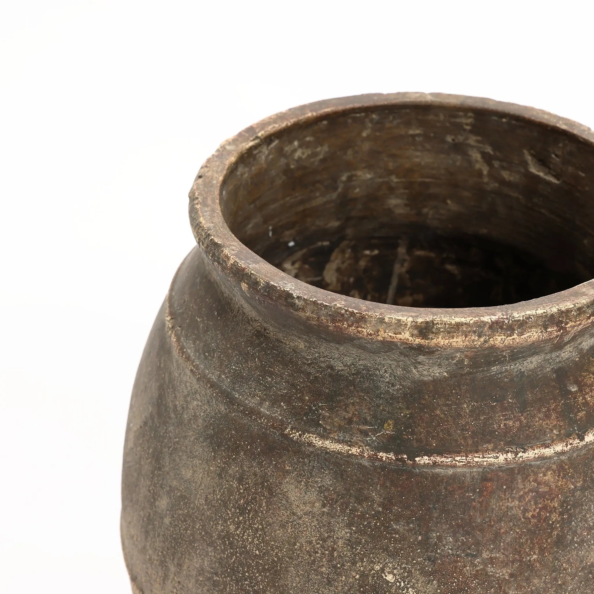 A close-up of a weathered, round terracotta urn vase with a wide, open top showcases its textured surface and earthy tones against a white background. This rustic piece is perfect for both indoor and outdoor settings.