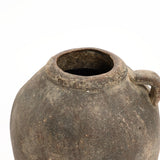 A rustic terracotta vase with a weathered, round shape features a wide opening and a small handle on one side, perfect for both indoor and outdoor use. Its handcrafted weathered finish stands out against the plain white background, offering timeless charm.
