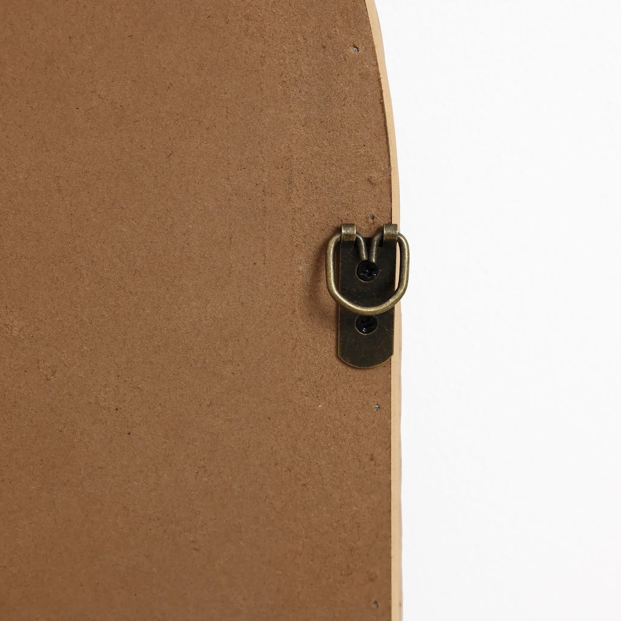 Close-up of a brass-colored metal picture frame hanger on the back of a wooden frame, resembling the elegant touch youd find in a bamboo-framed mirror. Set against a white background, it evokes the charm of a decorative hanging mirror with an arched rectangular design.