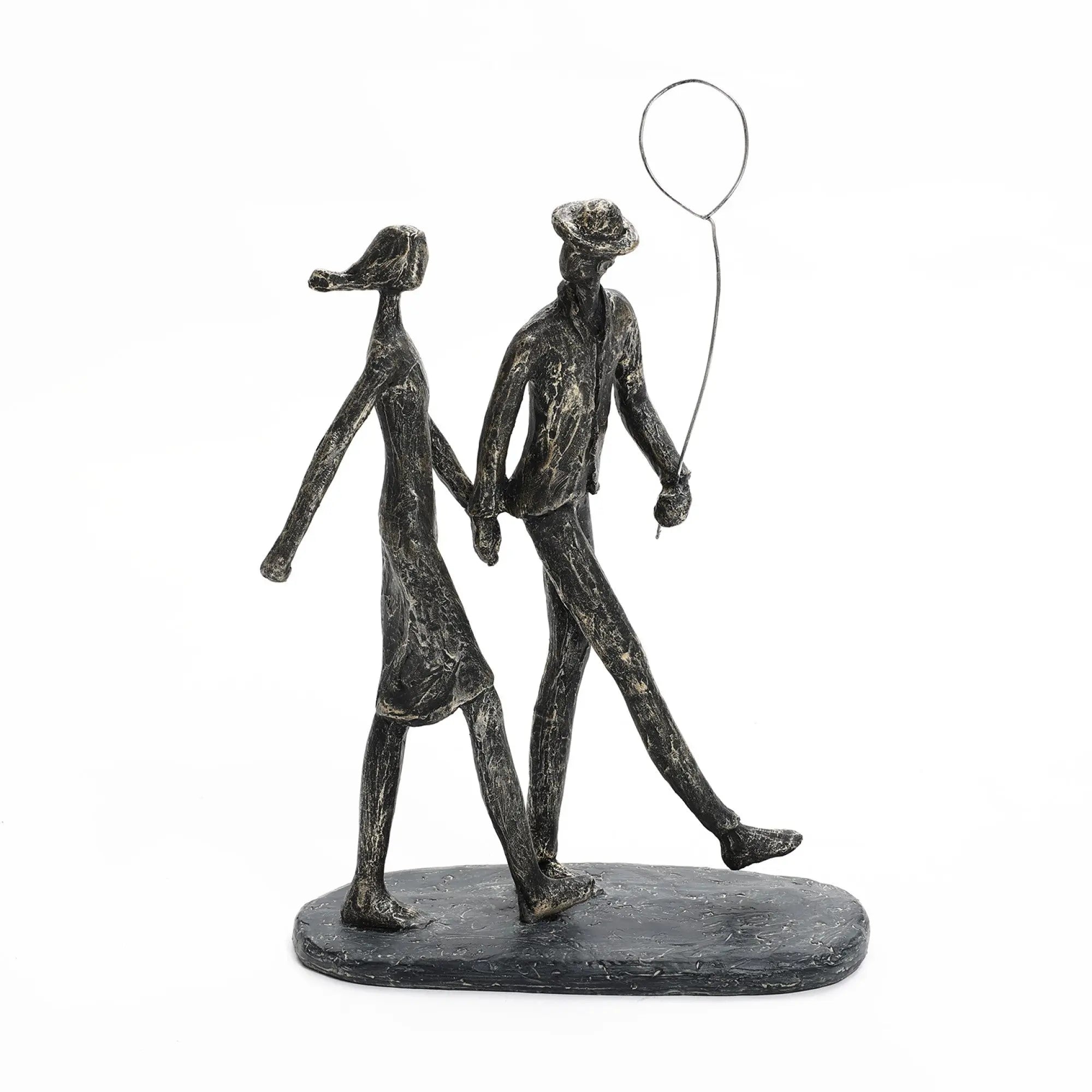 A modern resin home decoration, this stylized sculpture features two figures walking gracefully, one gently holding a balloon.