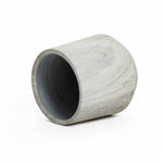 A gray, cylindrical concrete planter with a subtle marble ribbed texture lies on its side against a white background.