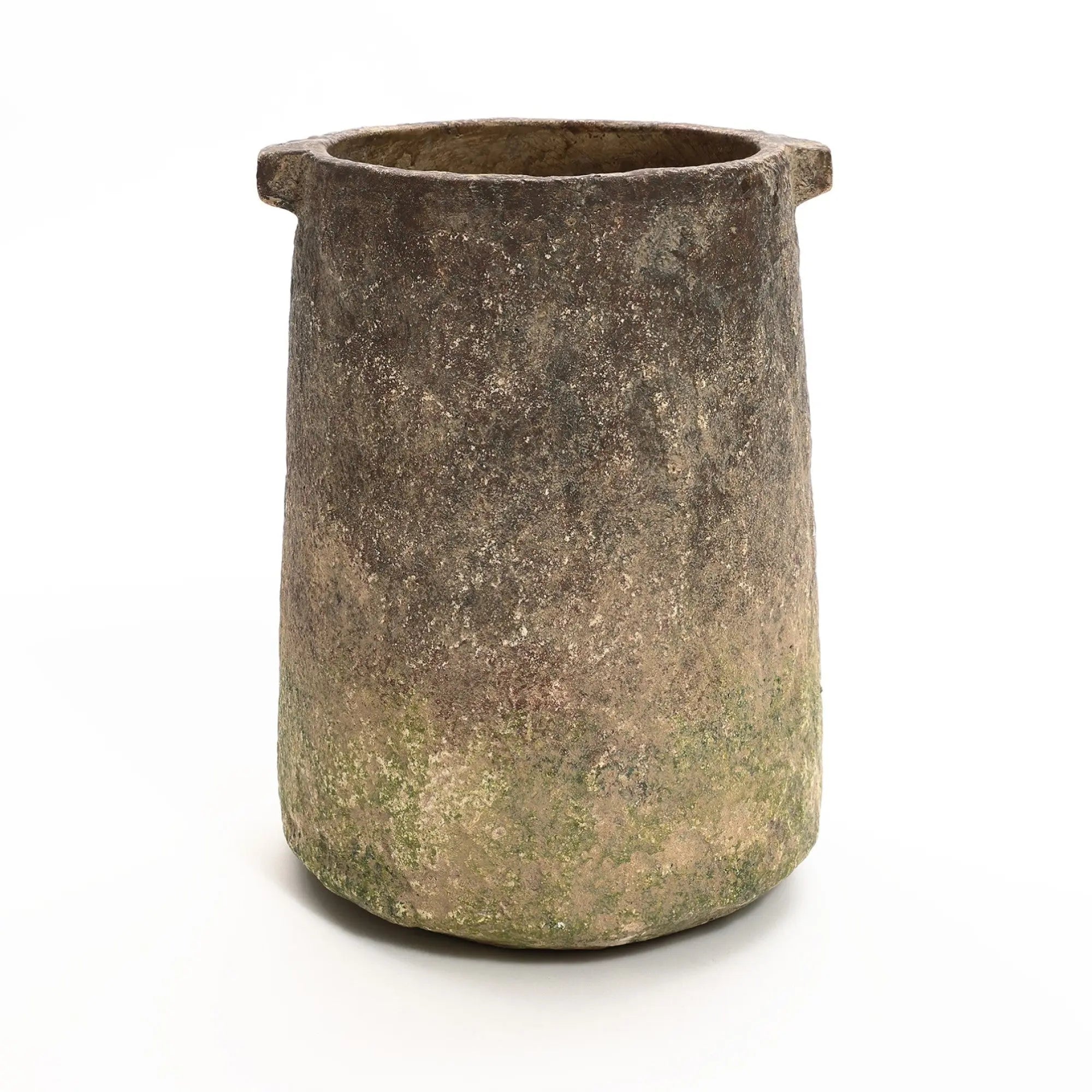 A weathered, cylindrical stone pot with two small handles near the top showcases a rustic ginger root brown finish. Its rough texture and shades of green and brown enhance its charm, making it reminiscent of a traditional rustic vase.