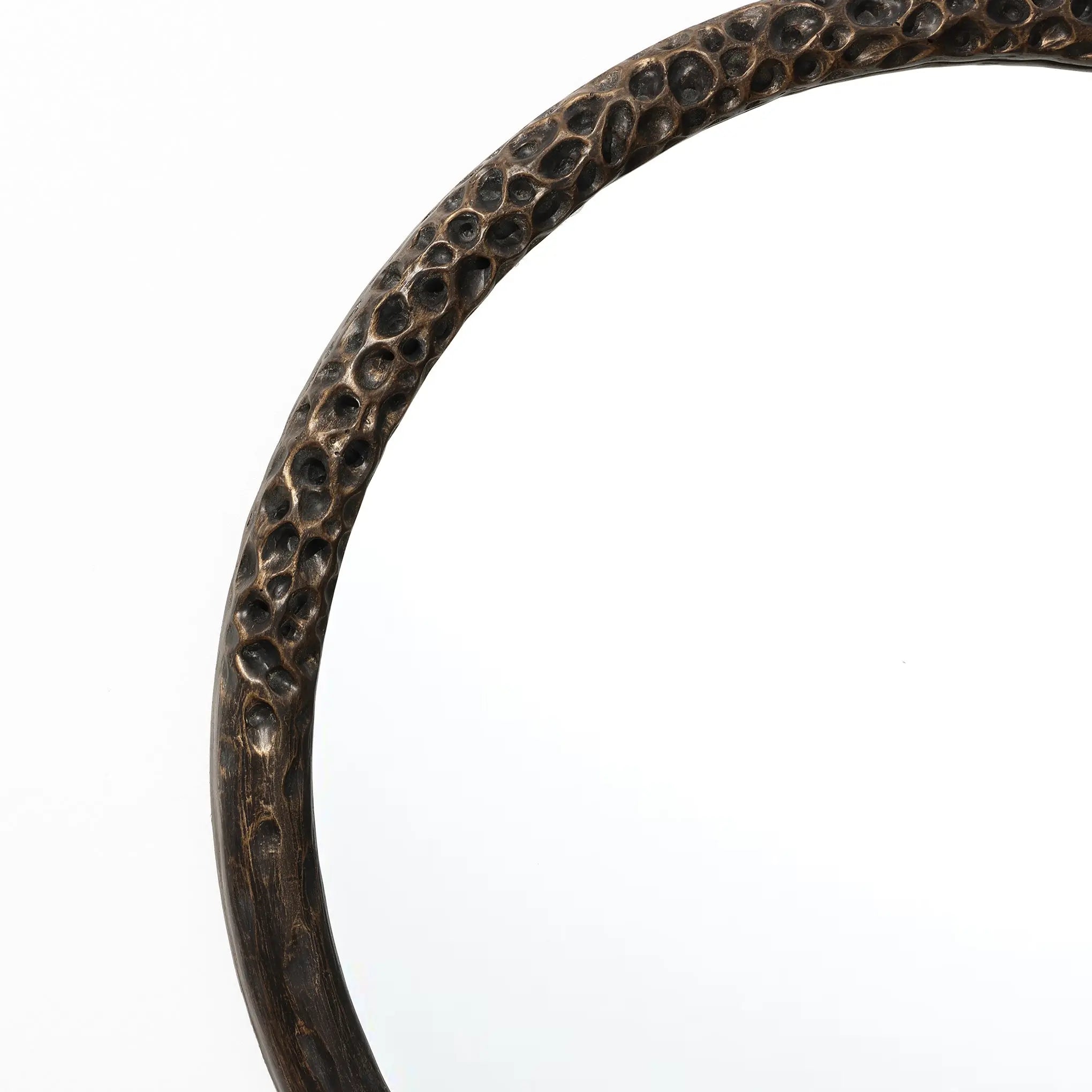 A close-up of LuxenHomes Aged Wood Finish Crater Pattern Round Wall Mirror showcases its brown frame with pebble-like designs. This industrial-style piece adds artistry against a plain white backdrop.