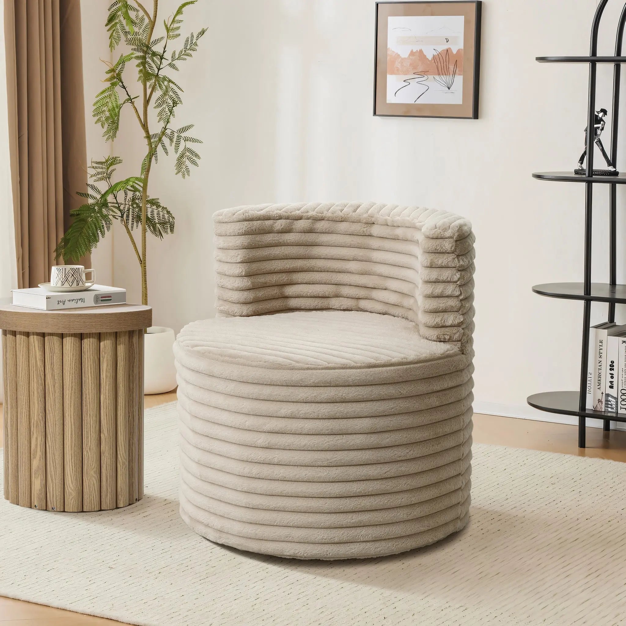 A modern living room showcases the LuxenHome Brie camel swivel barrel accent chair with a ribbed texture beside a wooden side table stacked with books. A framed abstract piece decorates the cream wall, while a black shelf and tall plant enhance the space.