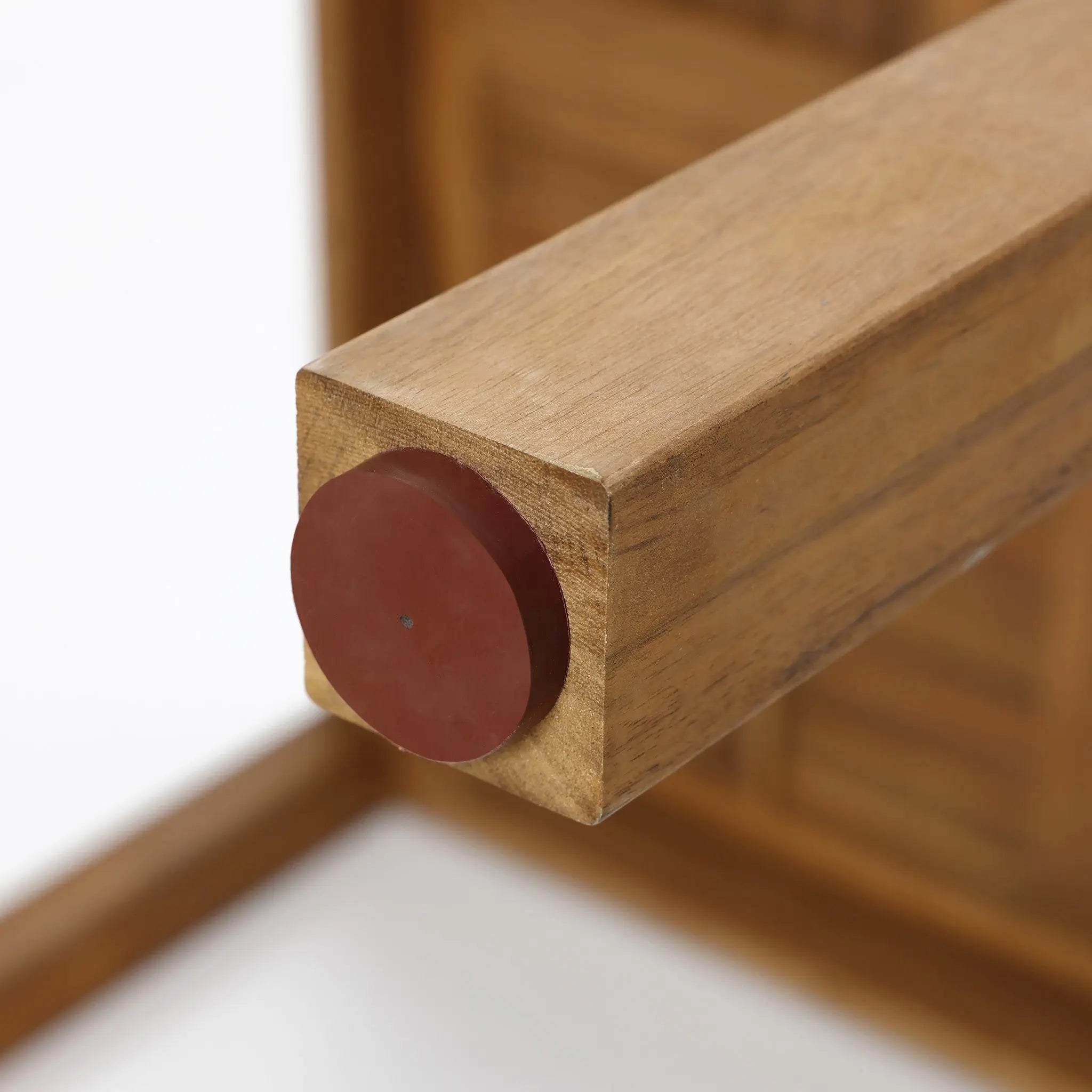Close-up of a wooden furniture leg crafted from FSC-certified acacia wood, featuring a circular brown plastic cap on the bottom. The light background highlights the rich texture of this sustainable material, perfect for an outdoor dining table.
