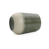 A green and white ceramic stool with a ribbed texture, featuring a convenient drainage hole, lies on its side. Perfect for indoor and outdoor environments, it can also double as a stylish planter.