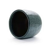 A LuxenHome Marina gray glazed round ceramic planter, 13.98 h, is artfully placed on its side against a white background, showcasing its textured interior and detailed exterior design.
