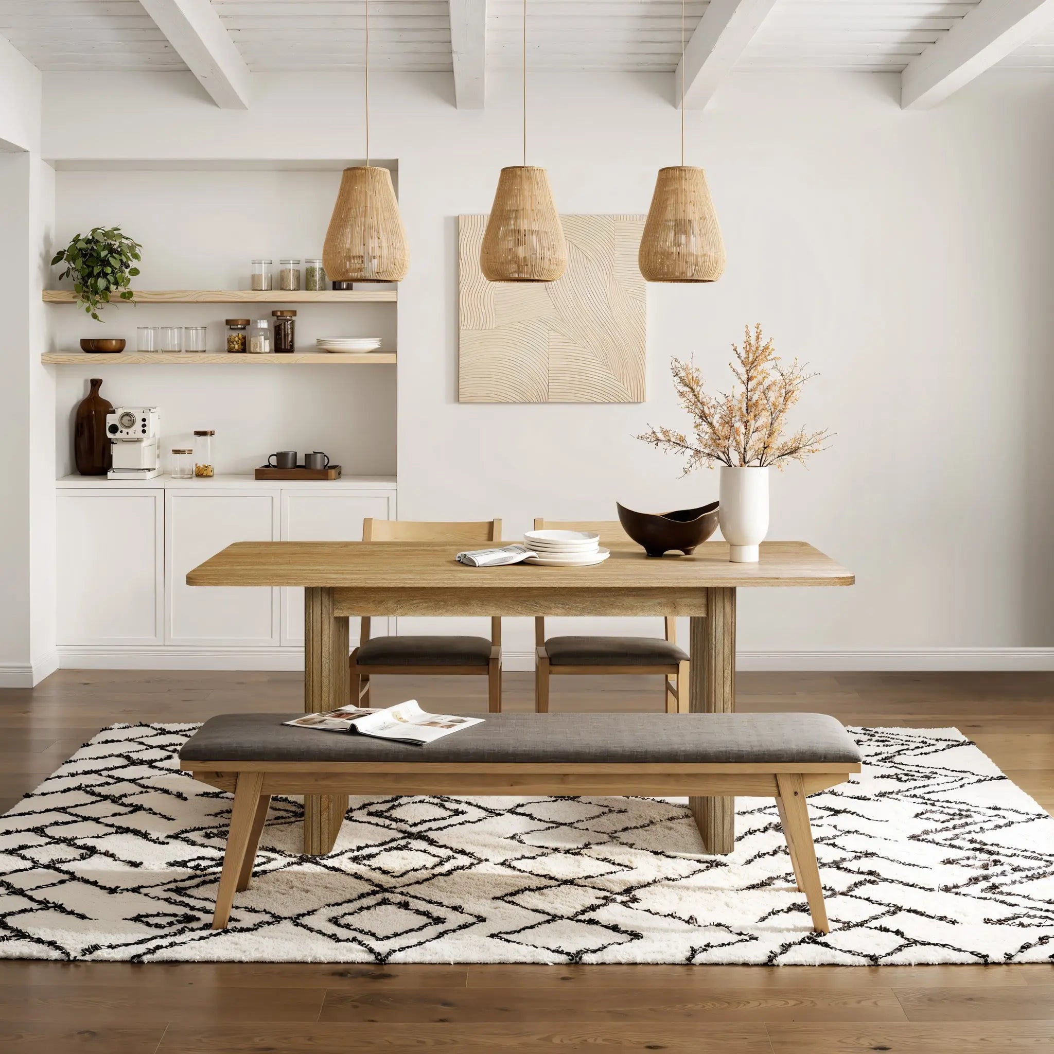 A modern dining area features the stylish LuxenHome Aria wood finish 63 dining table for six, accompanied by two chairs and a cushioned bench on a patterned rug. Three woven pendant lights add warmth, while a shelf with decor and a potted plant enhances the aesthetic against the white wall.