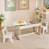 A childrens playroom features the LuxenHome Drawing and Activity Board Children Table with 2 Chairs Set, complete with built-in storage for colorful blocks. Two white chairs flank the table. Cheerful sun and rainbow wall art adorns the space, while a shelf displaying toys and plants stands in the corner.