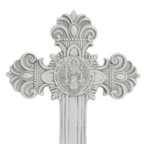 Silver decorative cross with ornate flourishes and an embossed image of a saint at the center, surrounded by inscriptions, perfect for celebrating religious occasions.
