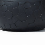 The LuxenHome Black beehive pattern round tabletop planter (17.5 w) features a dark, textured surface with interlocking pentagonal shapes. Its matte finish provides durability, while subtle lighting highlights the designs contours.