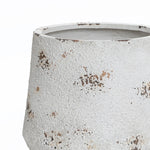 A textured, white ceramic pot with brown speckles and an unglazed rim, this round planter embodies a vintage minimalist style.