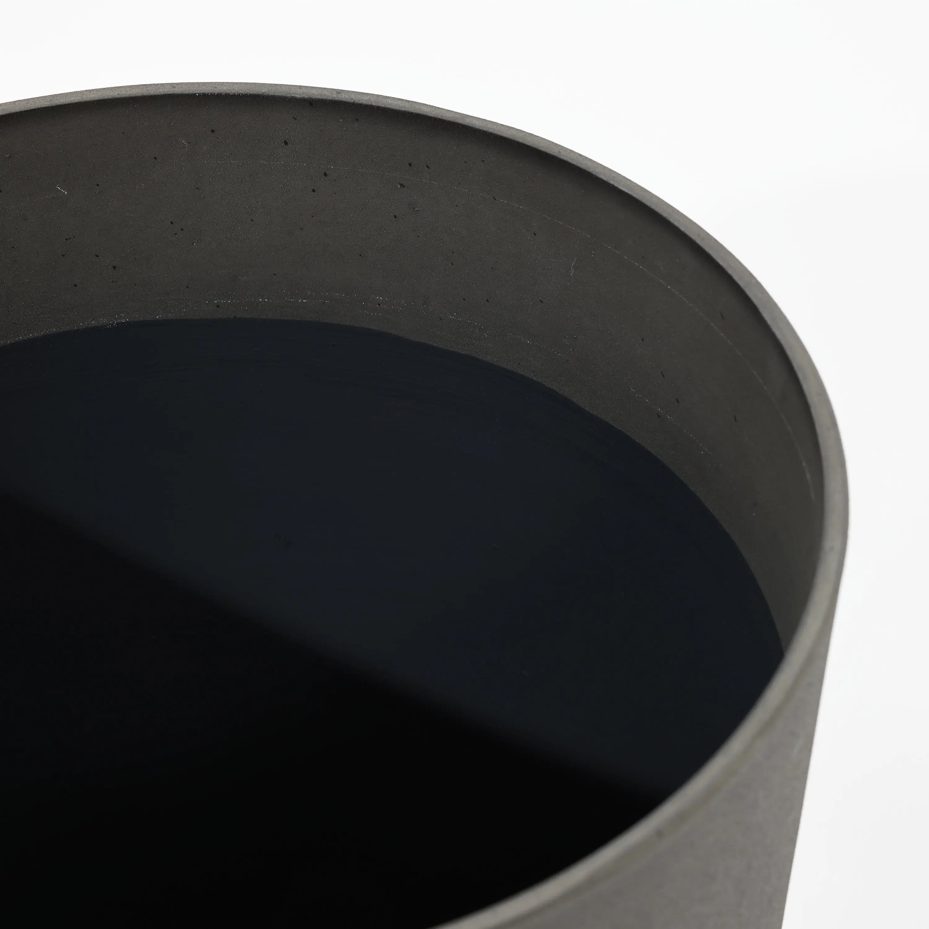 Top view of a durable, large, round black metal container filled with a dark, opaque liquid, reminiscent of a modern planter set.