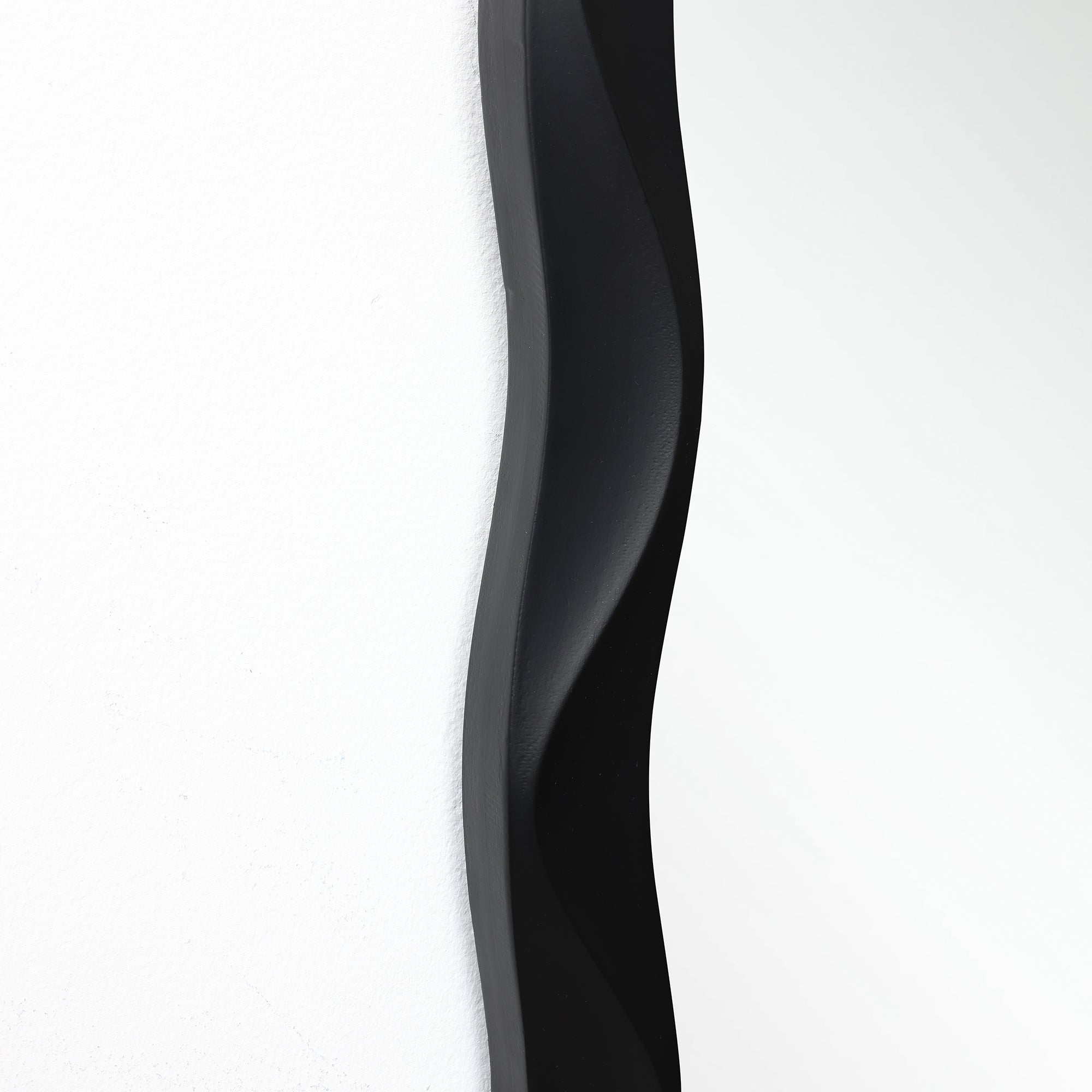 Close-up of highlighting the modern wall mirror’s curved design and clear reflection.