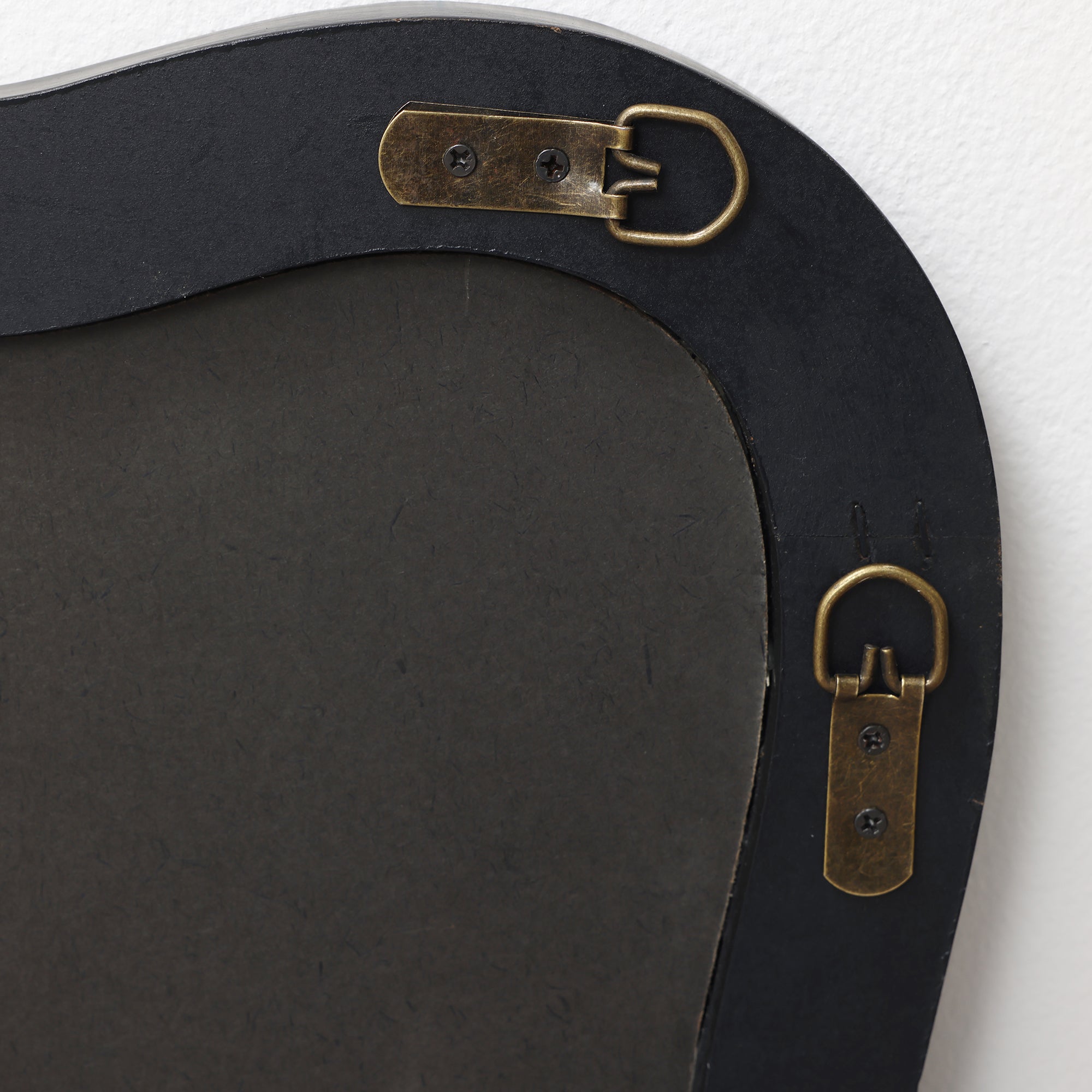 Close-up of the back, showing two brass hanging brackets attached with screws to a dark backing material.