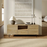 Light walnut-colored wood defines this wooden sideboard, topped with a lamp, books, and candlesticks. A textured wall art piece hangs above, adding to the mid-century modern charm. The room is bright with natural light and offers a glimpse of the adjoining living space.