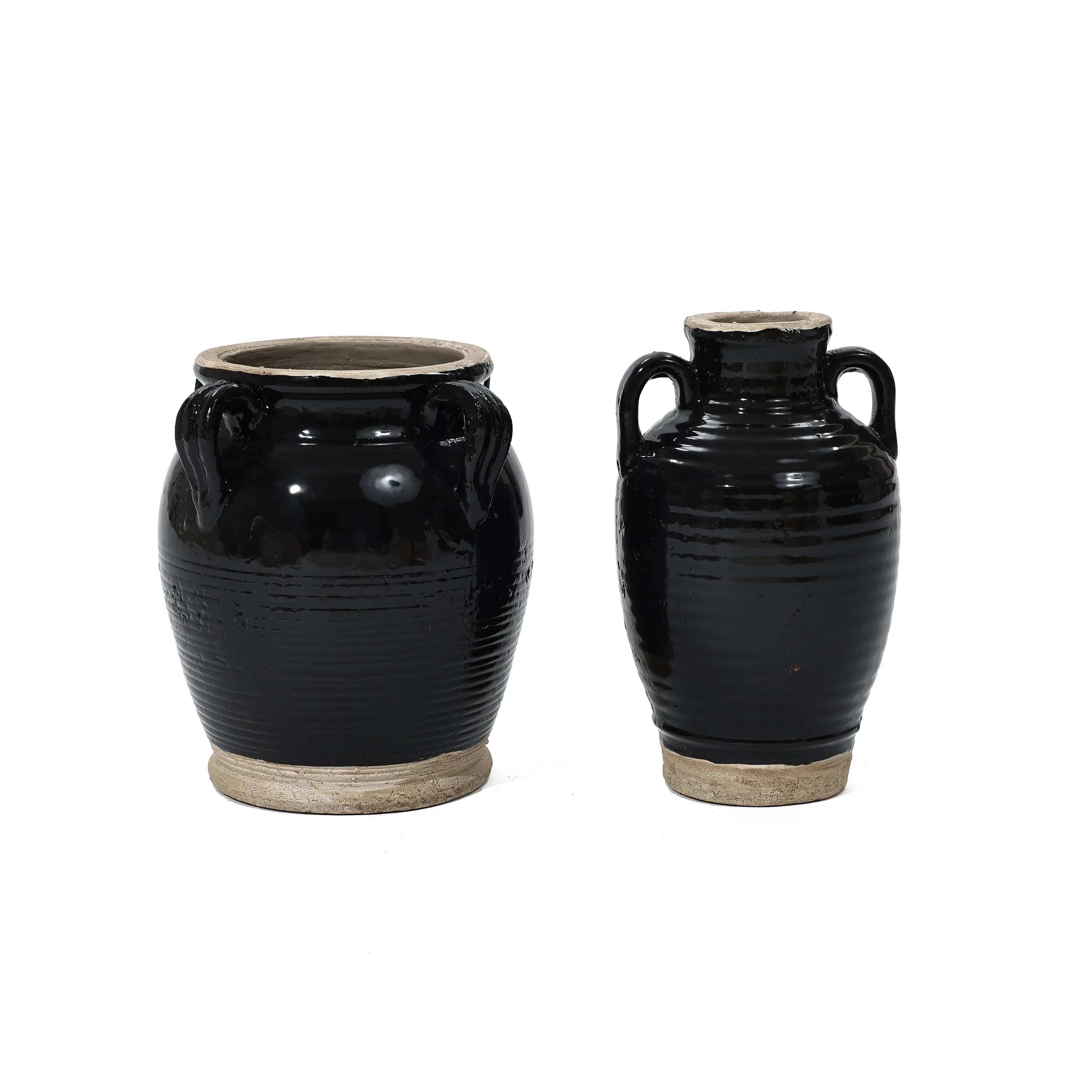 Two handcrafted black ceramic pots, finished with a smooth glaze, sit side by side against a plain white background. Their wide bases and small handles add to their simple elegance.