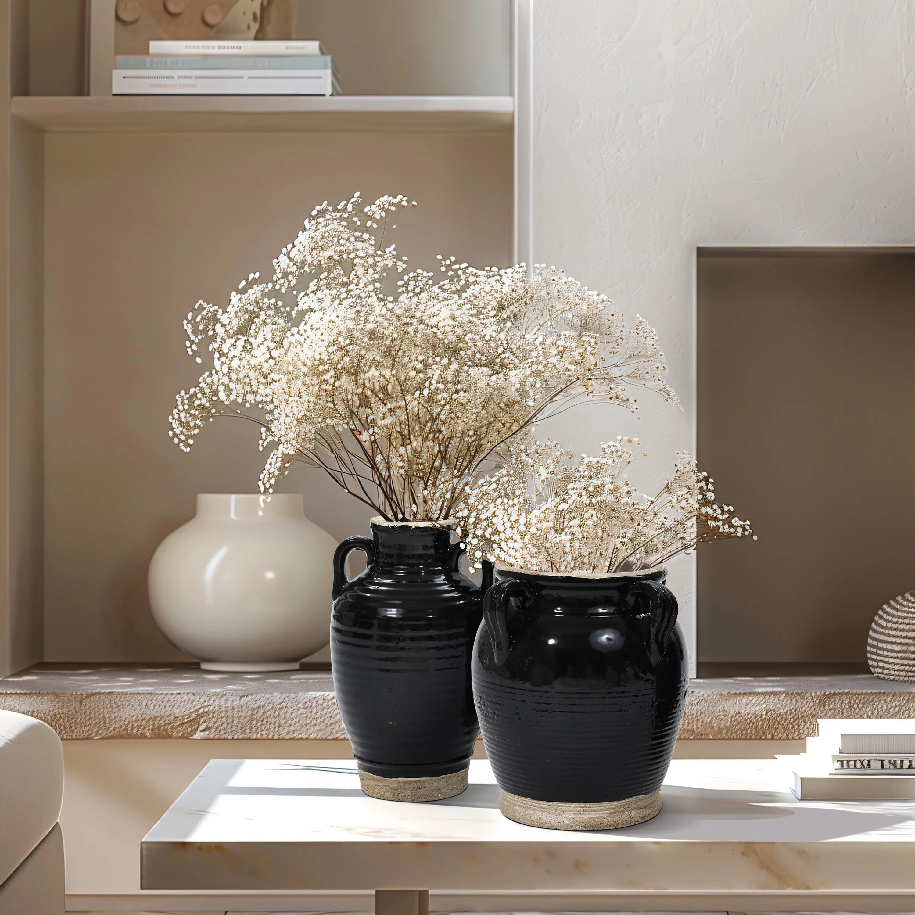 Two black-glazed vases with white flowers rest on a table, set against a minimalist background with soft lighting.