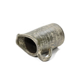 A weathered, cylindrical ceramic jug with a wide spout and a handle, lying on its side, showcases artisanal craftsmanship with a rustic terracotta finish.