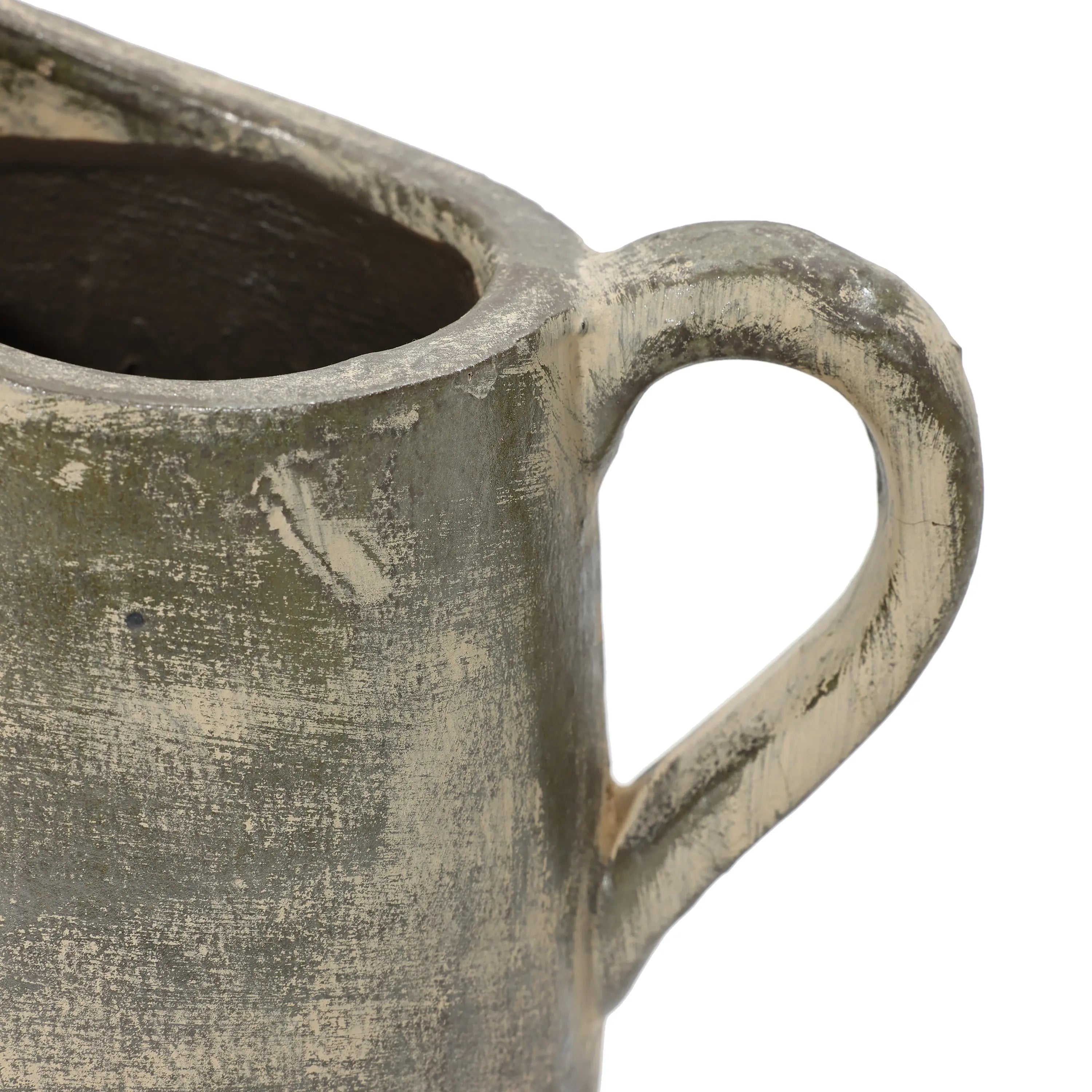 Close-up of a rustic, textured ceramic jug with a round handle and a partially visible open top, showcasing artisanal craftsmanship. The surface appears worn and uneven in color, reminiscent of a terracotta finish.