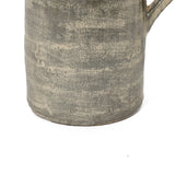 Close-up of the base of a textured ceramic mug with a handle, showcasing artisanal craftsmanship and a rustic, uneven grayish surface.