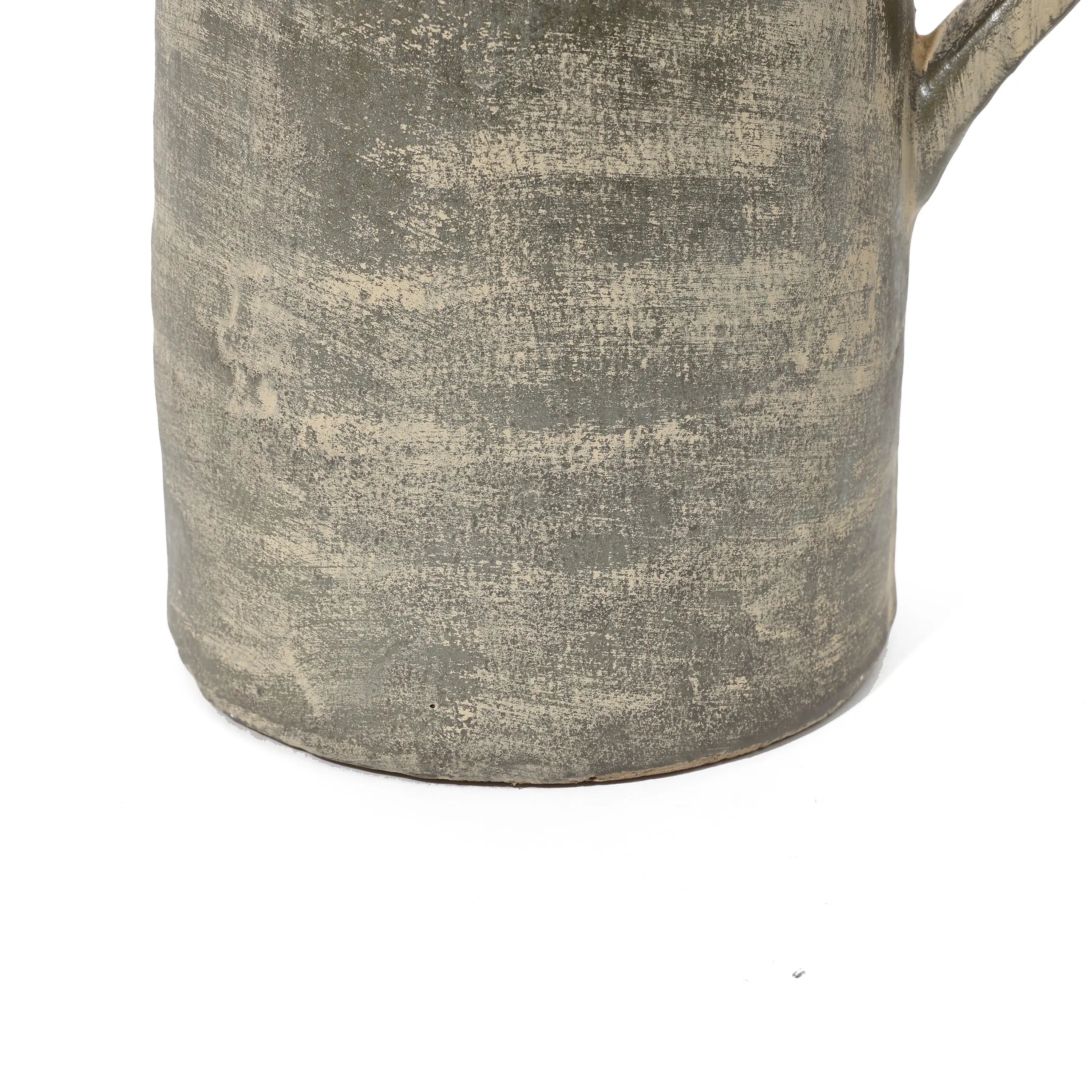 Close-up of the base of a textured ceramic mug with a handle, showcasing artisanal craftsmanship and a rustic, uneven grayish surface.