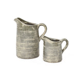 Two aged, gray ceramic pitchers of different sizes, showcasing artisanal craftsmanship against a white background, feature a subtle terracotta finish.