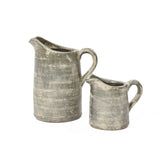Two aged, gray ceramic pitchers of different sizes, showcasing artisanal craftsmanship against a white background, feature a subtle terracotta finish.