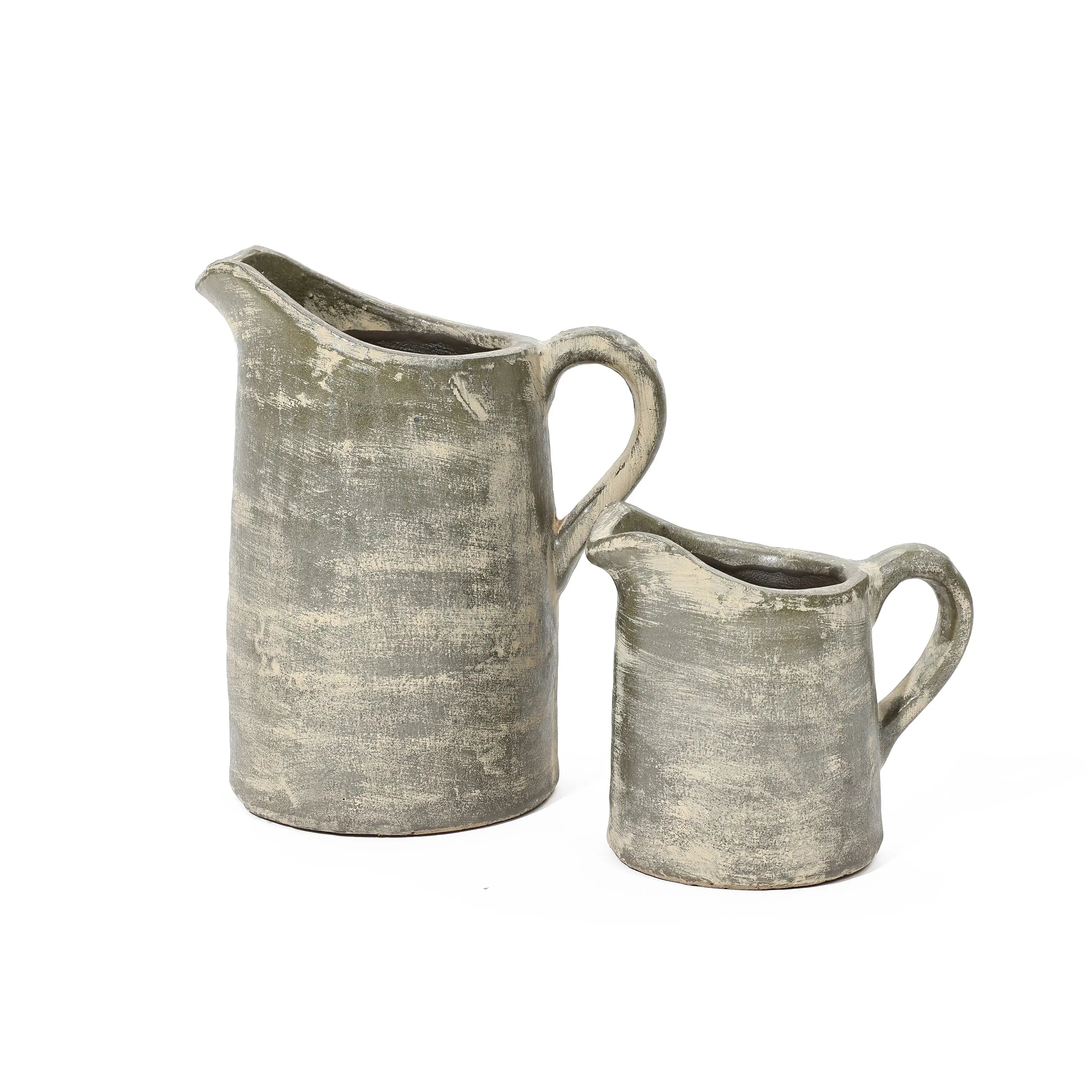 Two aged, gray ceramic pitchers of different sizes, showcasing artisanal craftsmanship against a white background, feature a subtle terracotta finish.