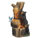 A decorative bear outdoor fountain features two black bears climbing a tree stump with a beehive, water flowing down and a blue bird perched on the edge—perfect for your garden or patio, crafted from durable resin.