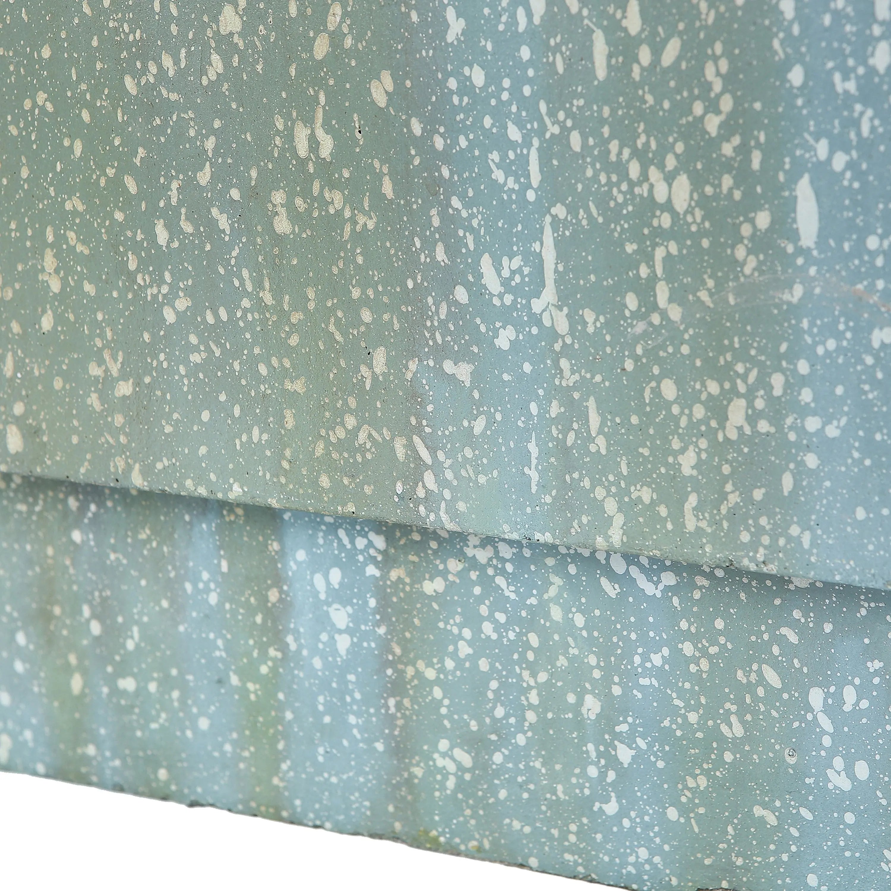 Close-up of a light blue surface with white paint splatters and a horizontal seam, reminiscent of a patio or garden wall near an outdoor fountain with the gentle sound of flowing water.