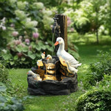 Outdoor garden scene featuring a resin water fountain with a goose and goslings, a water spout illuminated by an LED light, and surrounding greenery and flowers to enhance your outdoor space.