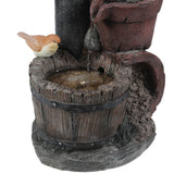 A small bird figurine sits on the rim of a rustic wooden bucket, with water trickling in from an upper spout, adding vintage farmhouse décor and rustic charm to any space.