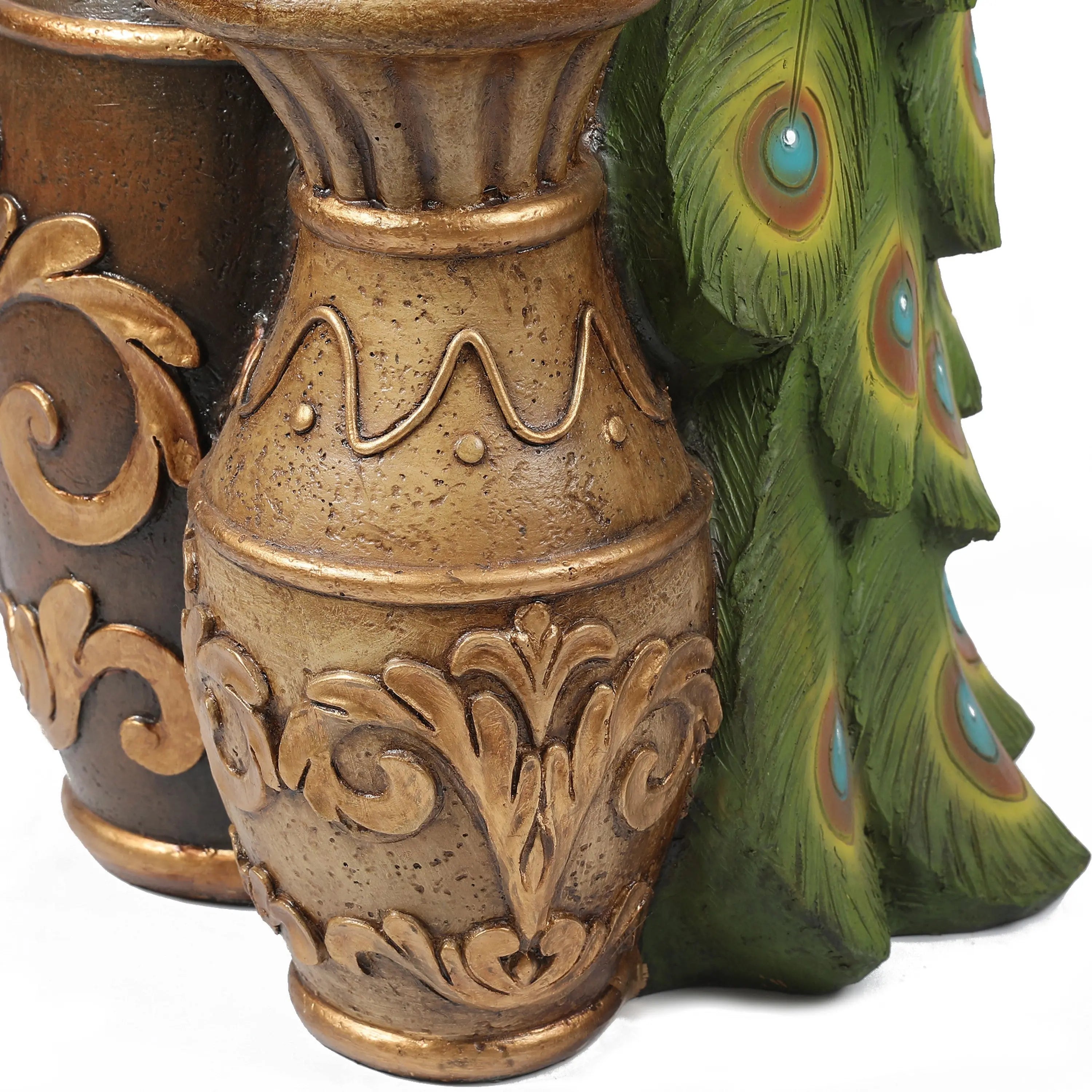 A decorative gold vase with ornate patterns stands next to green peacock feathers with blue and orange eye spots, creating a striking garden décor display.