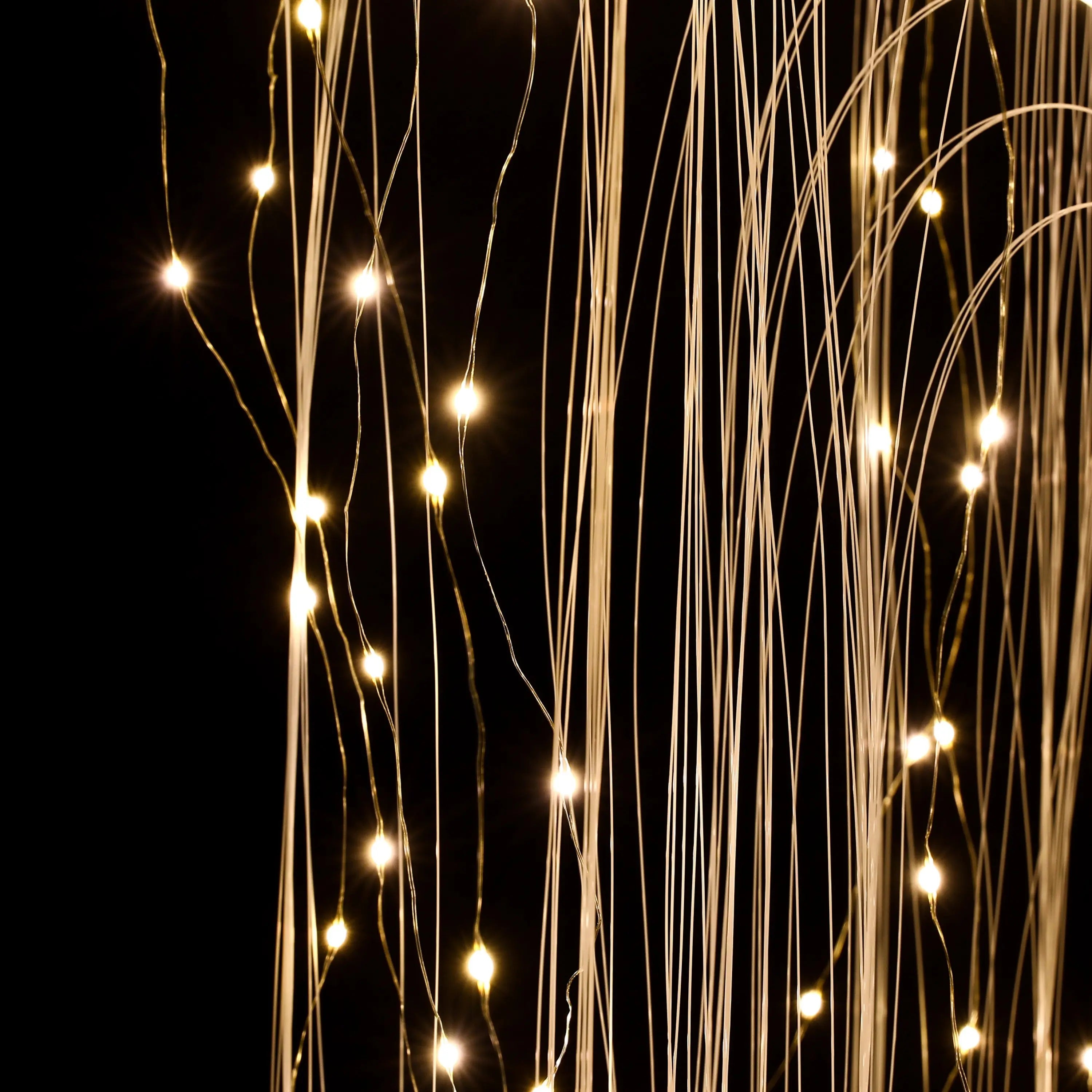 Thin strands of fiber optic cables with small white LED lights are shown glowing against a dark background.