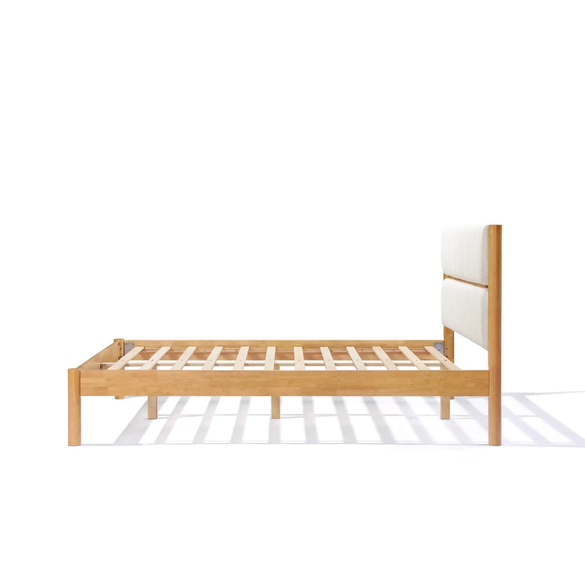 Solid wood bed with a light, luxurious white boucle fabric-upholstered headboard, shown from the side against a white background, exudes modern sophistication.