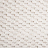 Close-up of a white textured fabric with a geometric, basket-weave pattern, adding a contemporary visual dimension reminiscent of an upholstered headboard.