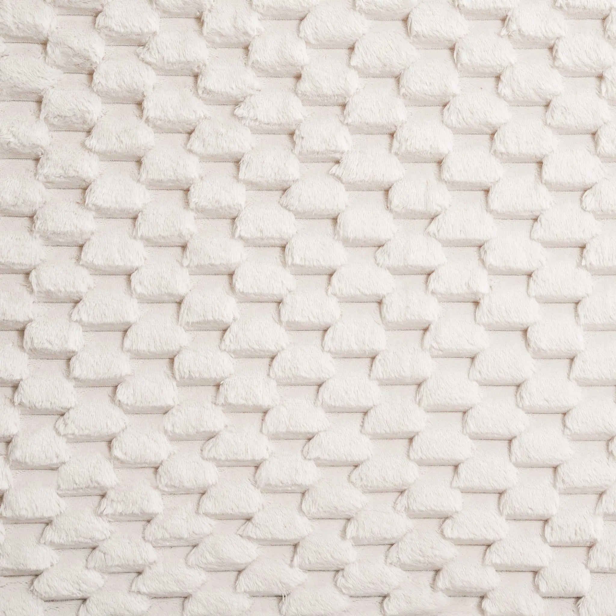 Close-up of a white textured fabric with a geometric, basket-weave pattern, adding a contemporary visual dimension reminiscent of an upholstered headboard.