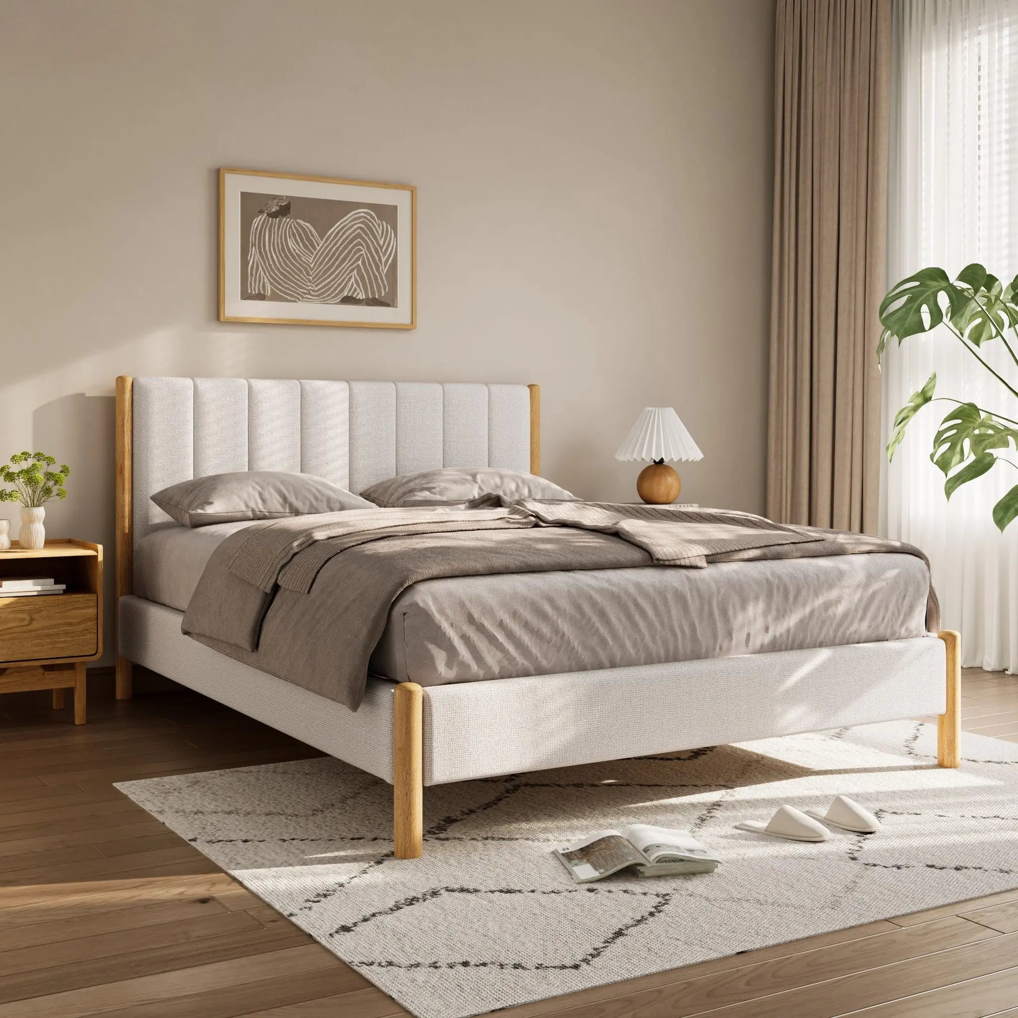 A neatly made bed with beige linens and a queen-sized white boucle headboard graces the sunlit bedroom, featuring a side table, lamp, framed artwork, and a large potted plant on a light-colored rug.
