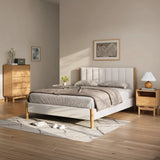 A minimalist bedroom features a rubberwood platform bed with a matching nightstand and dresser. Neutral bedding, a patterned rug, and framed wall art complete the decor. Natural light illuminates the room, highlighting the rooms stylish blend of simplicity and elegance.