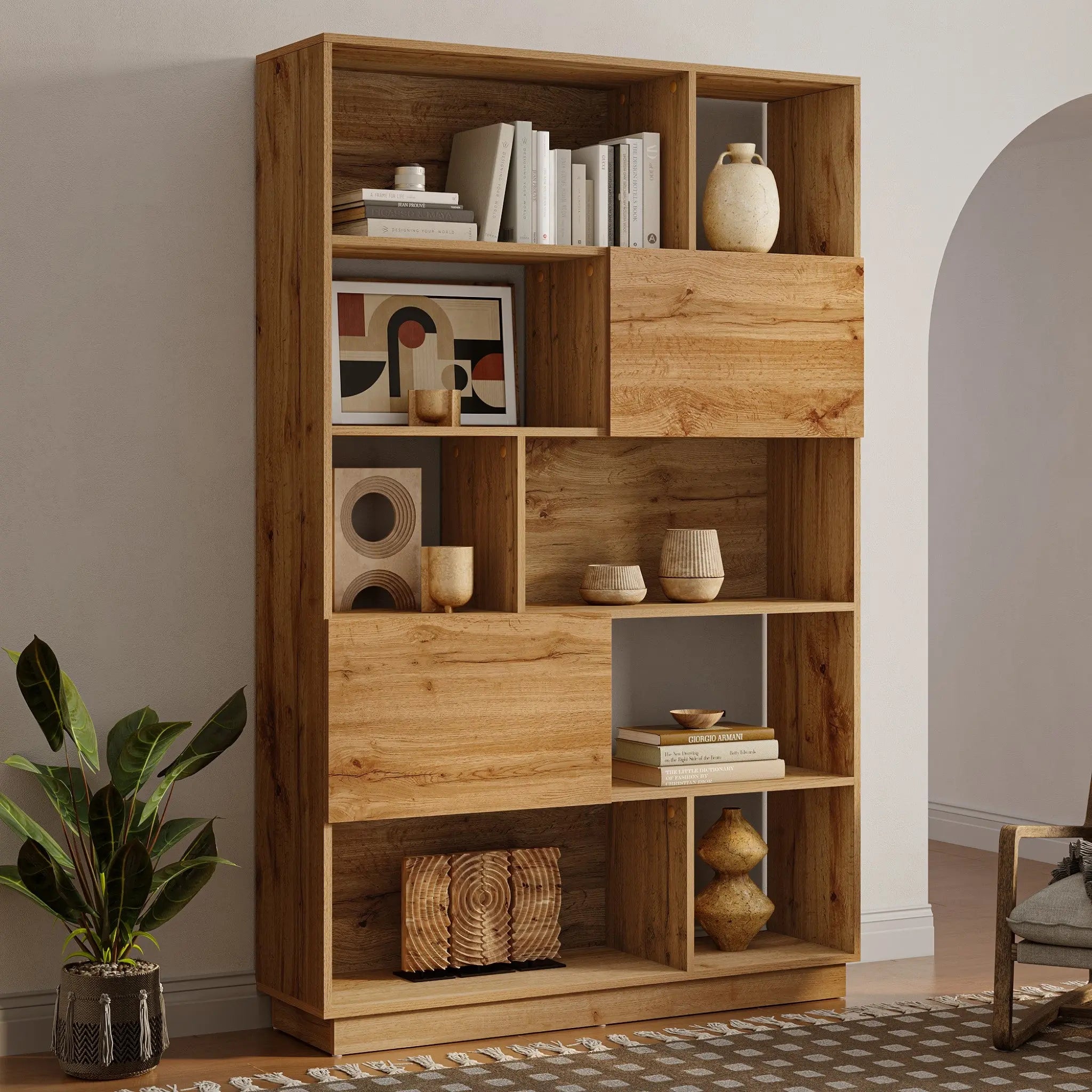Modern-style wooden bookshelf with asymmetrical compartments and a light walnut finish, holding books, decorative vases, and geometric art prints. A potted plant sits beside it on a patterned rug, offering ample storage space for your cherished items.